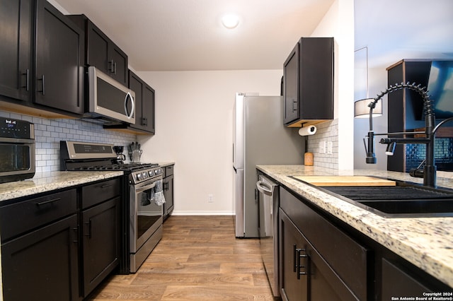 kitchen with light hardwood / wood-style flooring, backsplash, sink, and appliances with stainless steel finishes