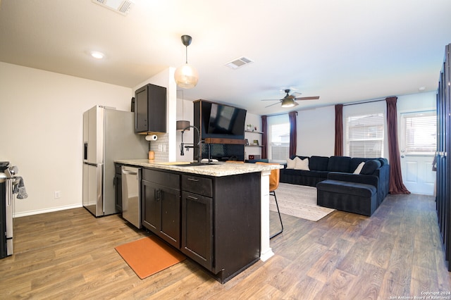 kitchen with decorative light fixtures, hardwood / wood-style floors, appliances with stainless steel finishes, kitchen peninsula, and ceiling fan