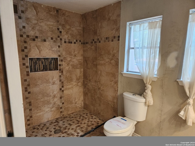 bathroom with toilet and a tile shower