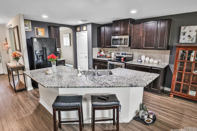 kitchen featuring backsplash, stainless steel appliances, a kitchen breakfast bar, sink, and an island with sink