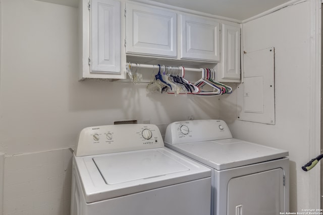 laundry area featuring electric panel, washing machine and clothes dryer, and cabinets