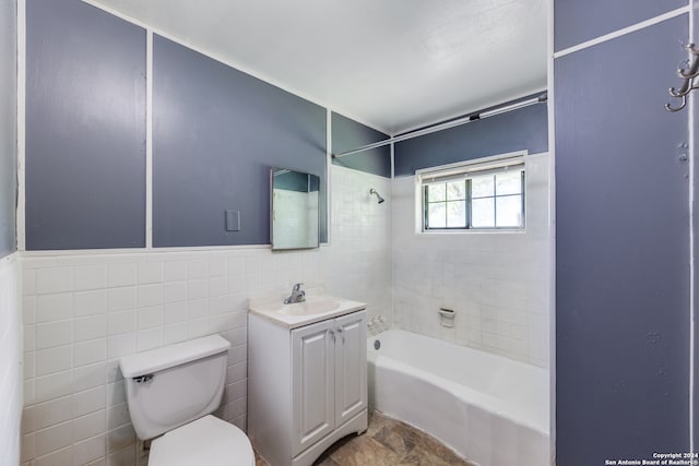 full bathroom with tile walls, toilet, tiled shower / bath combo, and vanity