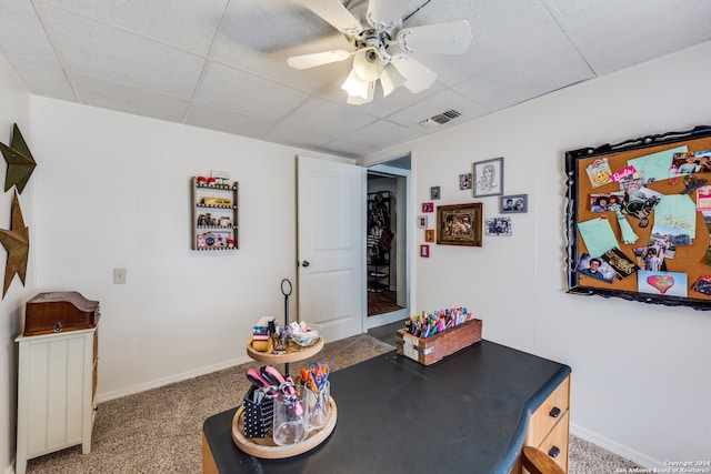 carpeted dining space with ceiling fan and a drop ceiling