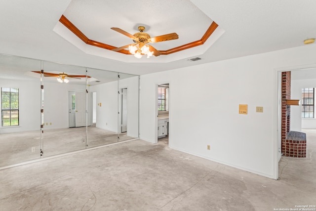 spare room with a textured ceiling, ceiling fan, crown molding, and a tray ceiling