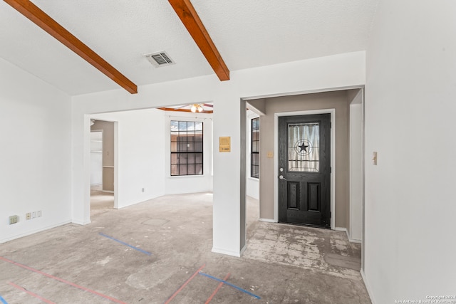 foyer featuring beamed ceiling, ceiling fan, and a textured ceiling