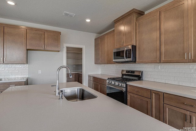 kitchen featuring stainless steel appliances, light countertops, visible vents, and a sink