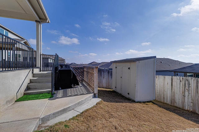 view of yard featuring a shed, a fenced backyard, and an outbuilding