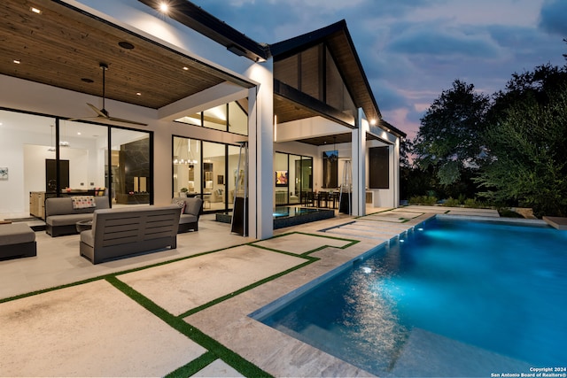 pool at dusk with a patio area, outdoor lounge area, and ceiling fan