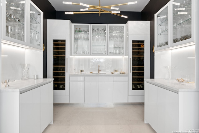 interior space featuring white cabinets, light stone counters, wine cooler, and sink