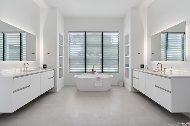 bathroom with tile patterned floors, a tub to relax in, and vanity