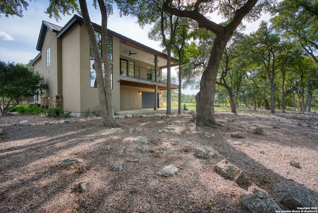 rear view of property featuring a balcony and ceiling fan