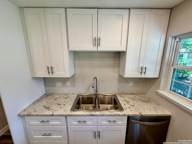 kitchen featuring stainless steel dishwasher, sink, and white cabinets