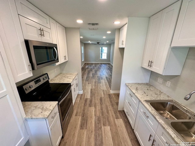 kitchen with white cabinets, appliances with stainless steel finishes, light hardwood / wood-style floors, and sink