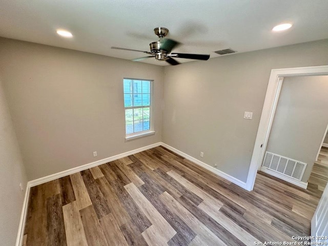 spare room featuring visible vents, a ceiling fan, baseboards, and wood finished floors