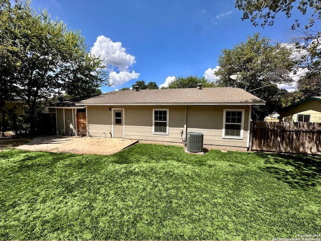 rear view of house featuring central AC unit, fence, a lawn, and a patio