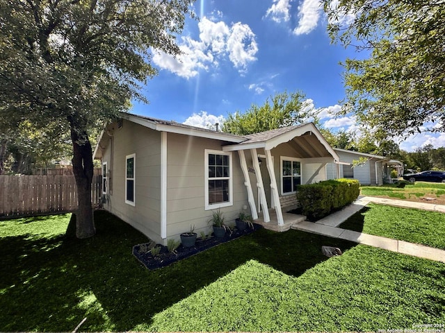 view of front of home featuring driveway, a front lawn, and fence