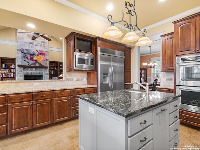 kitchen with built in appliances, ornamental molding, backsplash, a center island, and dark stone countertops