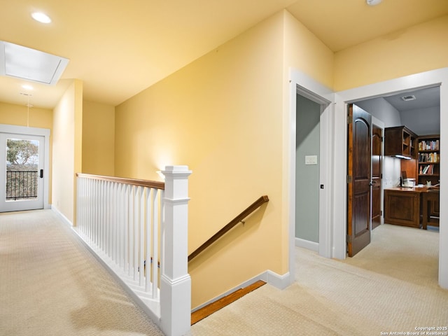 corridor with carpet floors, attic access, baseboards, and an upstairs landing