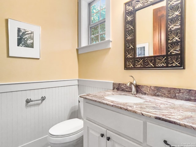 bathroom with wainscoting, vanity, and toilet