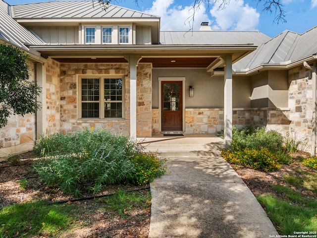 property entrance with metal roof, stone siding, a porch, and a standing seam roof