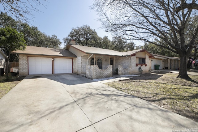 ranch-style home featuring brick siding, a chimney, an attached garage, cooling unit, and driveway