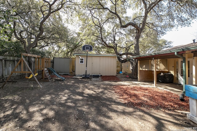 view of yard featuring a playground, a storage unit, an outdoor structure, and fence