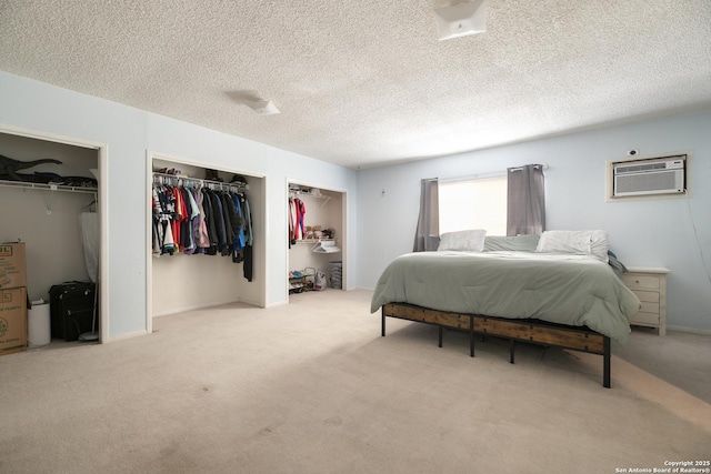 carpeted bedroom with a wall mounted air conditioner, a textured ceiling, and two closets