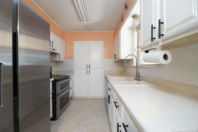 kitchen with under cabinet range hood, stainless steel appliances, a sink, white cabinetry, and light countertops