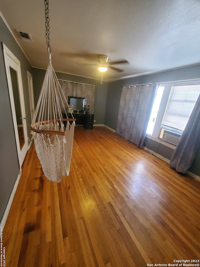 unfurnished room with cooling unit, ceiling fan, and wood-type flooring