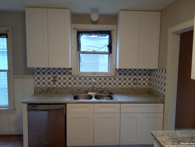 kitchen with stainless steel dishwasher, sink, backsplash, and white cabinetry