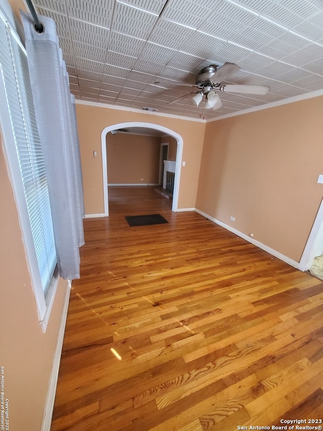 unfurnished living room featuring ceiling fan, crown molding, and light hardwood / wood-style flooring