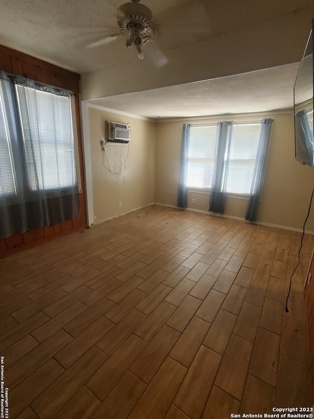 unfurnished room with a wall mounted air conditioner, a textured ceiling, hardwood / wood-style flooring, and ceiling fan