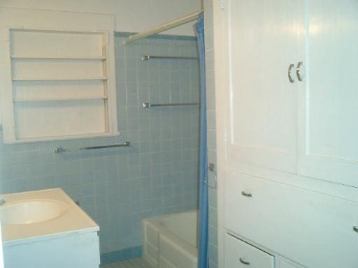 bathroom featuring tiled shower / bath, vanity, and tile walls