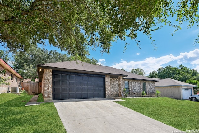 view of front facade featuring a garage, a front yard, and cooling unit