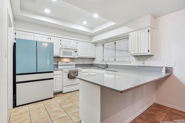 kitchen featuring white cabinetry, a raised ceiling, white appliances, and kitchen peninsula