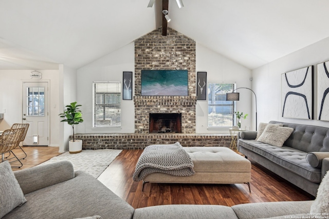 living room with dark wood-type flooring, ceiling fan, vaulted ceiling with beams, and a brick fireplace