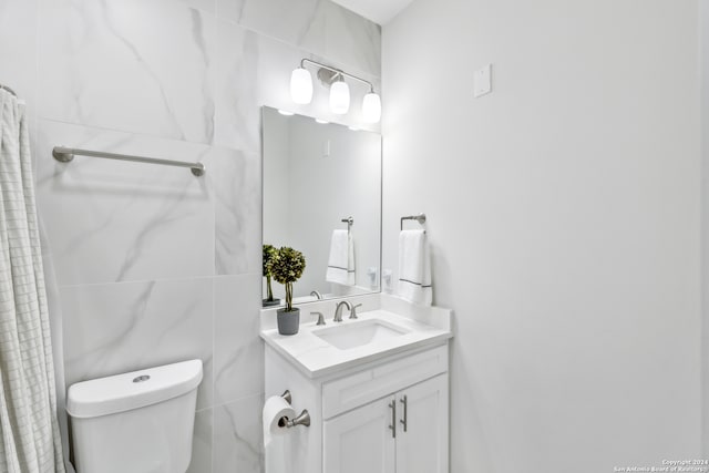 bathroom with vanity, toilet, and tile walls