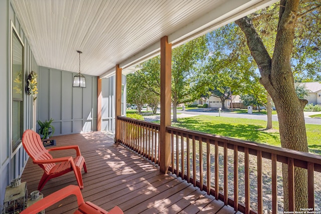 wooden terrace with covered porch and a lawn