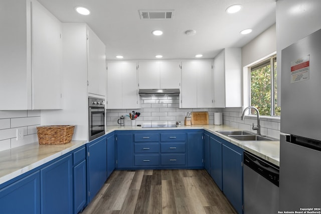 kitchen featuring white cabinets, blue cabinetry, appliances with stainless steel finishes, dark hardwood / wood-style flooring, and sink