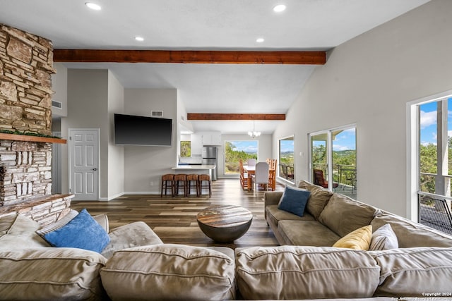 living room with dark hardwood / wood-style flooring, a wealth of natural light, a stone fireplace, and vaulted ceiling with beams