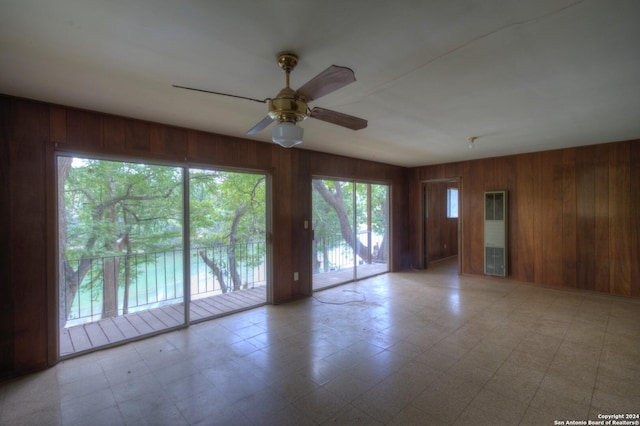 spare room featuring wood walls, light floors, and ceiling fan