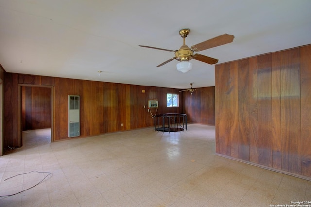 spare room with light floors, ceiling fan, and wooden walls