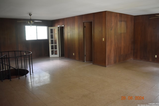 unfurnished room featuring ceiling fan and wood walls