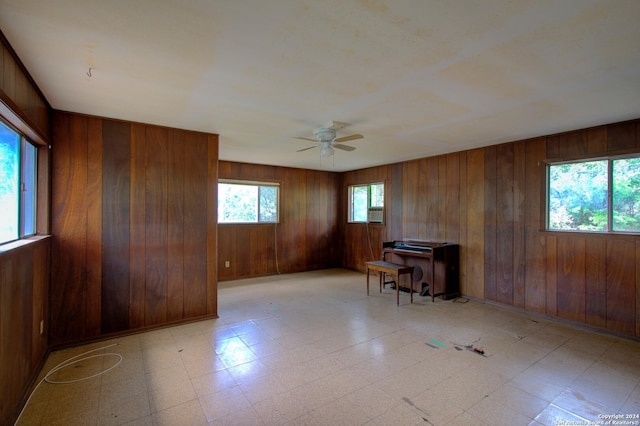 spare room with wooden walls, light floors, a healthy amount of sunlight, and a ceiling fan
