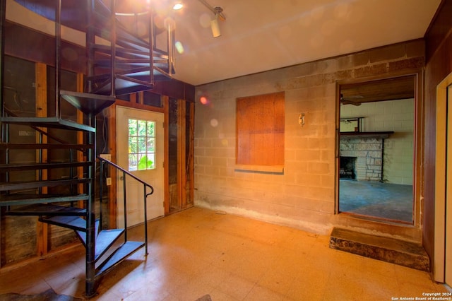 basement featuring tile patterned floors, stairway, concrete block wall, and a fireplace
