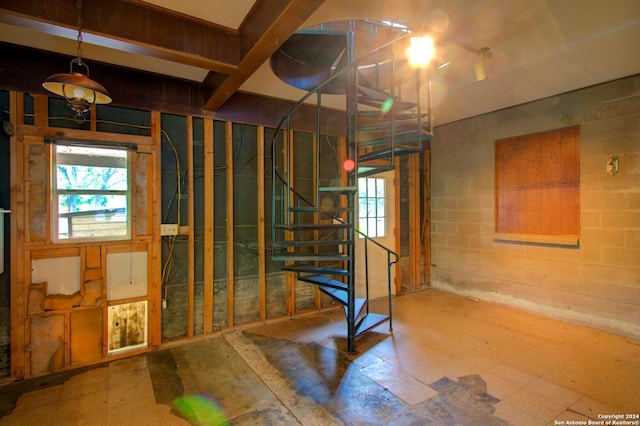 basement featuring stairs, tile patterned floors, and concrete block wall