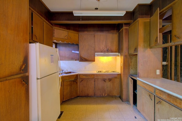 kitchen featuring white appliances, light floors, a sink, light countertops, and under cabinet range hood
