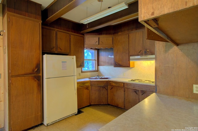 kitchen with under cabinet range hood, light floors, light countertops, white appliances, and a sink