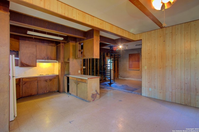 basement featuring stairway, light floors, wooden walls, and freestanding refrigerator