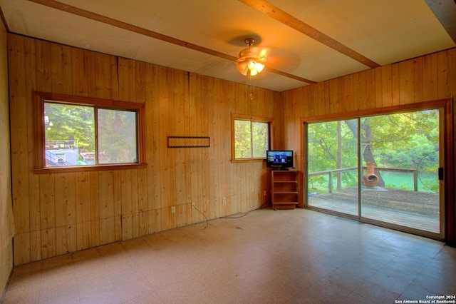 empty room featuring tile patterned floors, wooden walls, and a ceiling fan